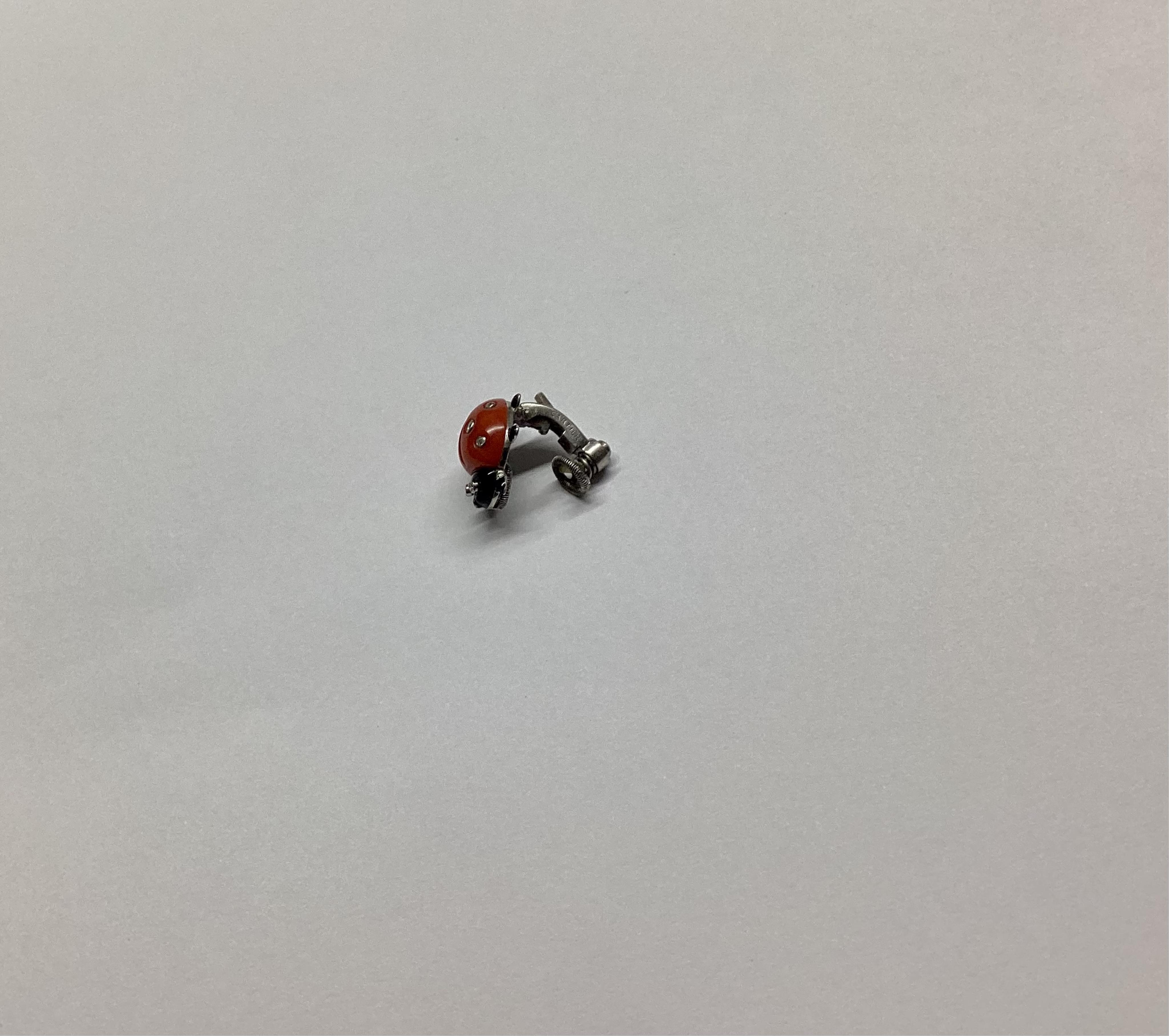 A pair of white metal, enamel, coral and diamond ladybird ear clips, bearing Cartier, New York signature and inscribed 18k